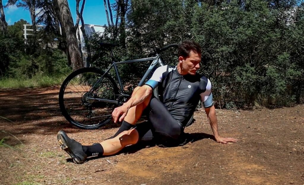 Cyclist stretching and rehydrating after a long-distance bike ride for recovery