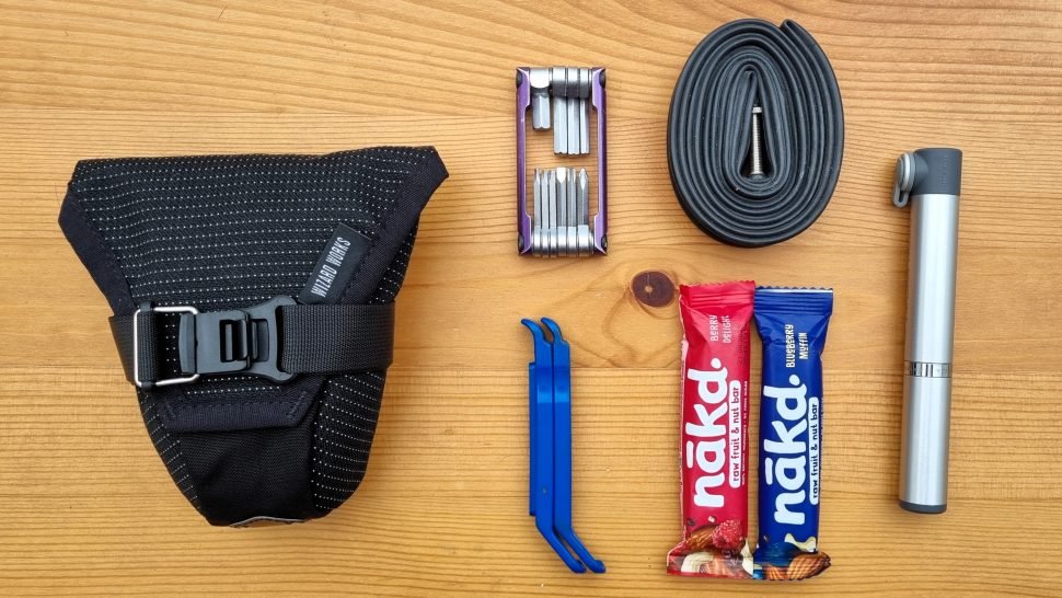 Essentials for a long-distance bike ride: hydration, snacks, and safety tools in a saddlebag.